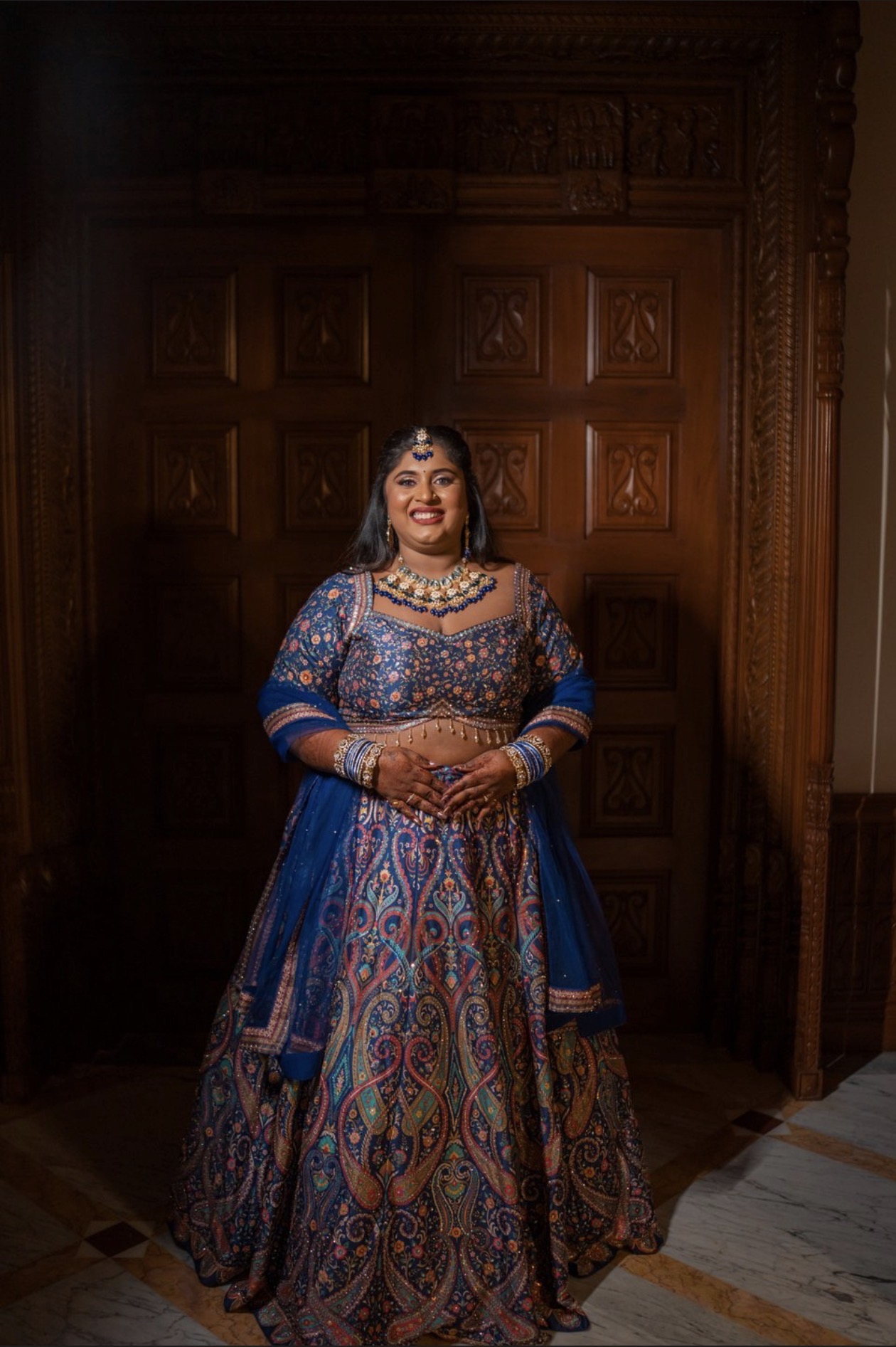 Dr. Ashvini Sundararaju in a blue lehenga before a carved wooden door